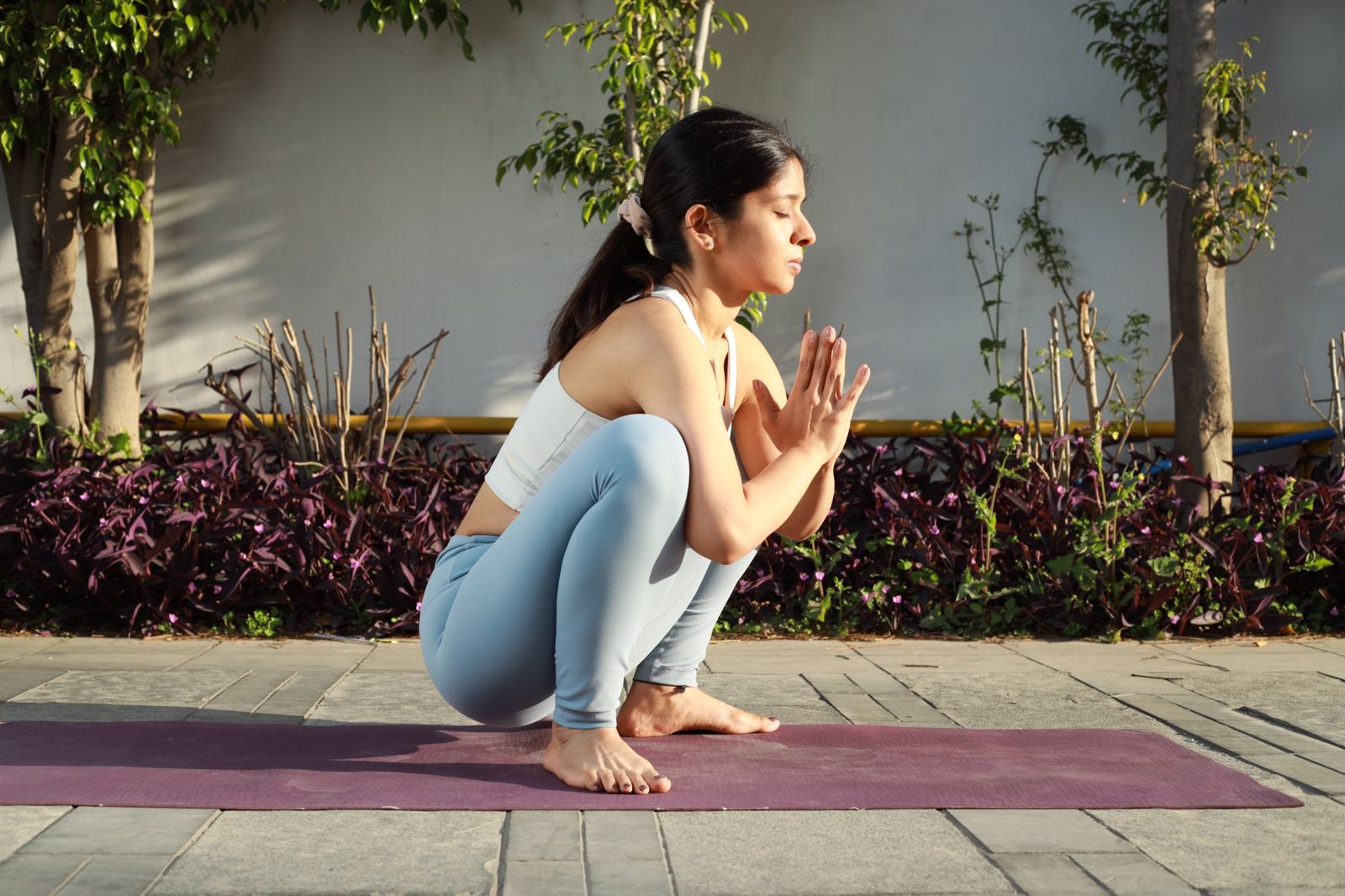 Juhie in a deep squat with hands in prayer