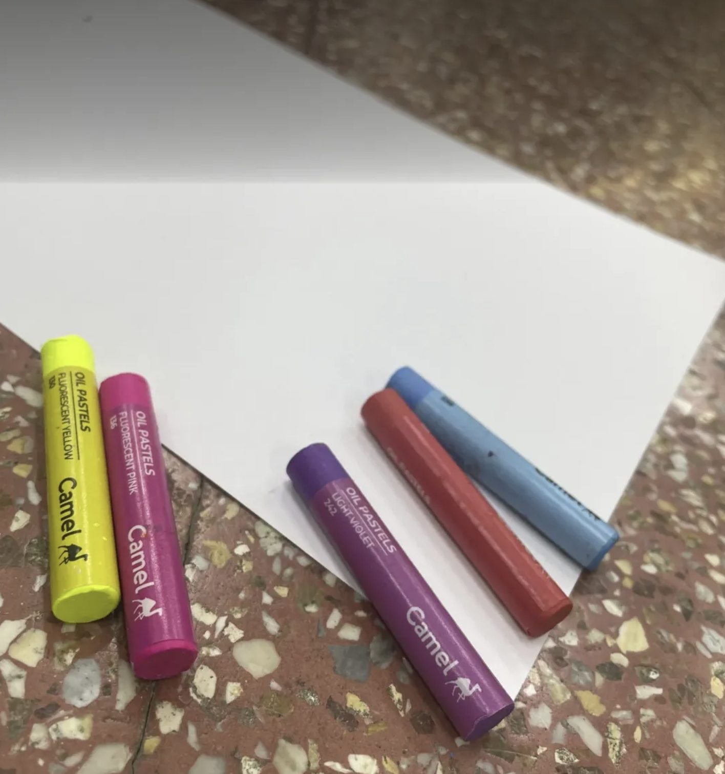 Oil pastels laid out on a sheet of white paper, ready for an expressive arts session
