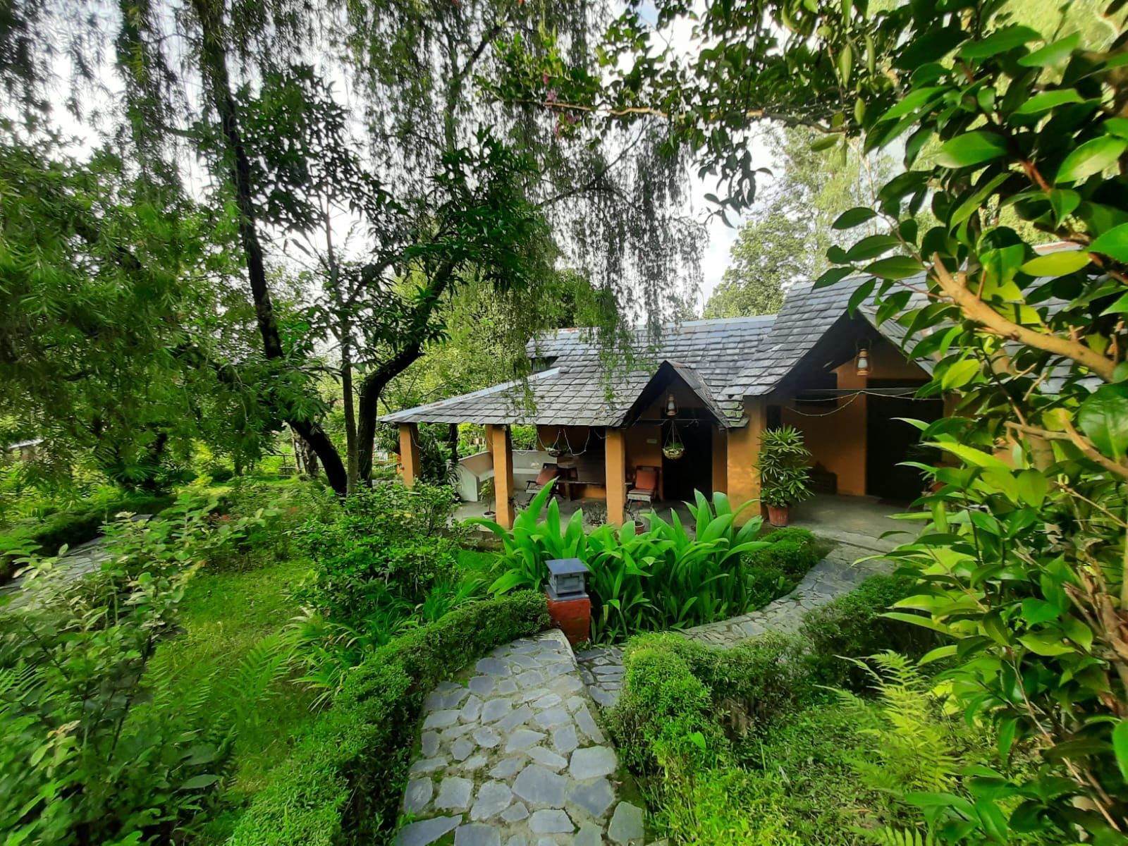 A restored Himachali cottage in a green garden at The Mirage, Andretta